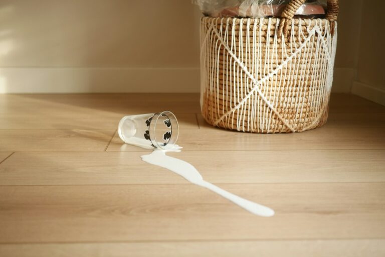 Person gently cleaning a hardwood floor with a microfiber mop near a bright home entryway.